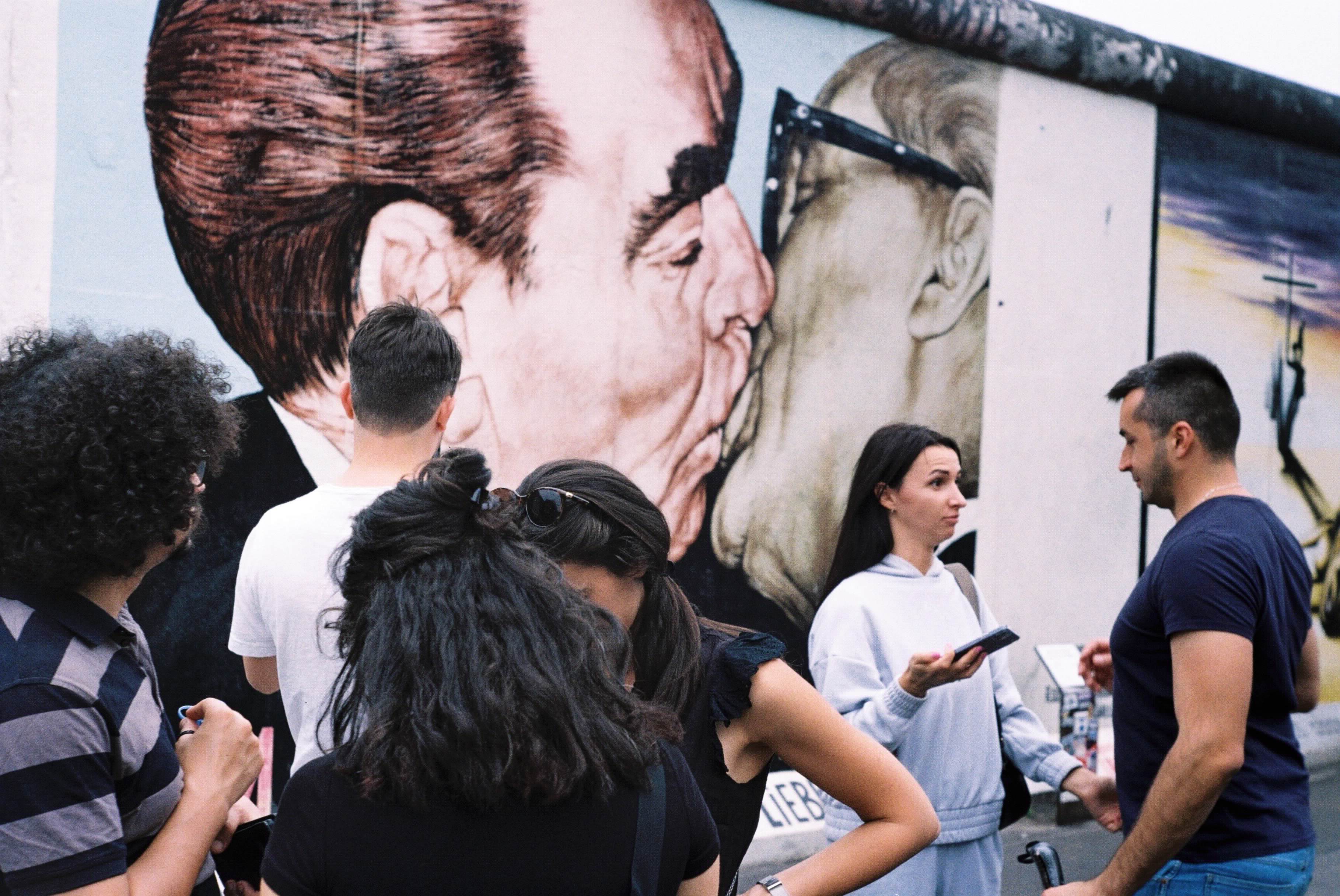 Tourists at the famous kissing mural on the berlin wall.